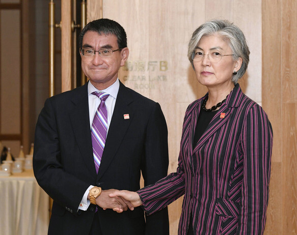 South Korean Foreign Minister Kang Kyung-wha and Japanese Foreign Minister Taro Kono shake hands before their meeting in Beijing on Aug. 21. (Yonhap News)