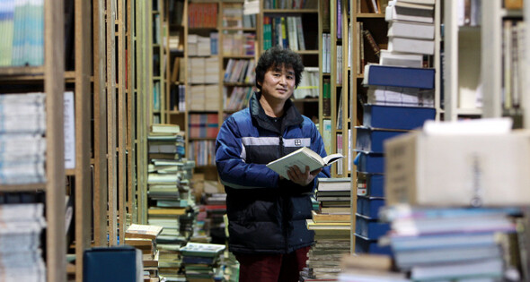 60여 평인 그의 창고는 웬만한 도서관을 방불케 했다. 남문서점이 보유한 책은 20만 권이나 된다. 지난 2월8일 윤한수씨가 서가에서 책을 들고 서 있다.