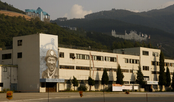 강원도 정선 사북읍의 옛 동원탄좌 건물에 탄광 노동자 걸개그림이 걸려 있다. 그 뒤편 위로 정선 카지노 건물이 보인다.