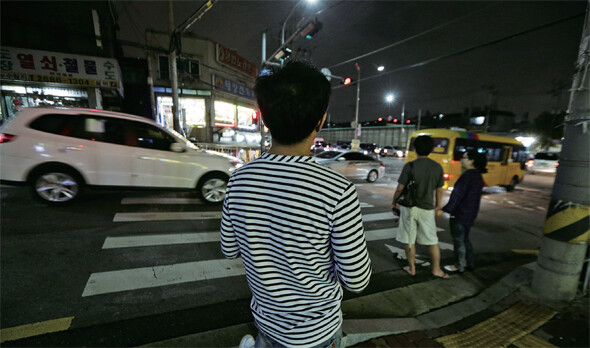 서울에서 홀로 생활하는 한 난민이 횡단보도에서 신호가 바뀌기를 기다리고 있다.