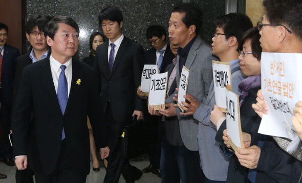 안철수 새정치민주연합 공동대표가 28일 오전 국회에서 여당이 제안한 기초연금법 개정안 수용 여부를 논의하려고 비공개로 열린 의원총회장으로 향하는 동안 회의장 들머리에서 국민연금바로세우기국민행동 등 시민단체 대표자들이 기초연금법안에 반대하는 팻말시위를 벌이고 있다. 이정우 선임기자 woo@hani.co.kr