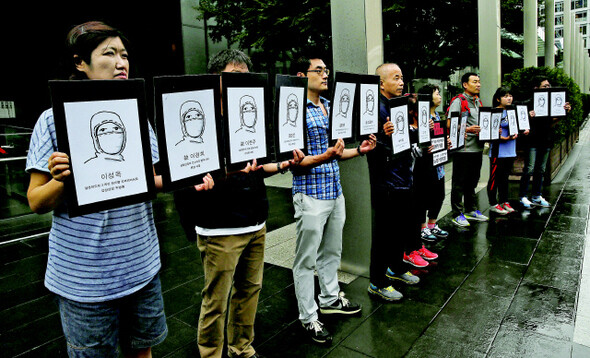  families and members of civic groups hold placards with the faces of those who died from diseases contracted at Samsung factories