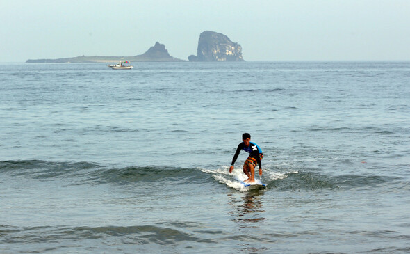 형제섬이 멀리 보이는 사계리 해안에서 서핑 시범을 보이고 있는 성용훈씨. 한겨레21 정용일 기자 yongil@hani.co.kr
