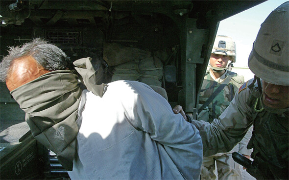2003년 4월, 미군이 이라크 바그다드를 점령한 뒤 사담 후세인 친위조직 ‘페다인 사담’ 등의 저항이 이어졌다. 미군 병사들이 사담 후세인의 고향 티크리트에서 페다인 사담의 일원으로 의심되는 사람을 체포해 장갑차에 태우고 있다.  AP