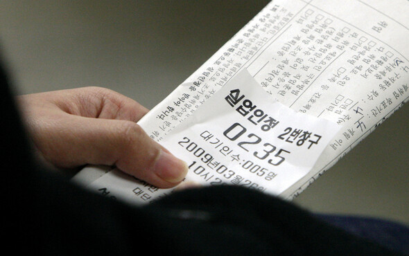 한 여성 실업자가 3월26일 오전 서울 마포구 도화동 서울서부종합고용지원센터에서 번호표와 신청서를 들고 실업급여 신청 순서를 기다리고 있다.