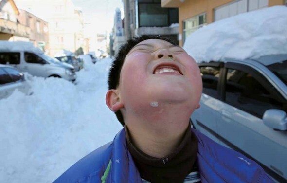 폭설로 휴교령이 내려진 가운데 집 앞에서 친구들과 눈싸움을 하며 즐거워하는 아이.