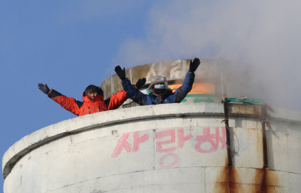 지난해 12월31일 경기 평택시 칠괴동 쌍용자동차 굴뚝에서 복직을 요구하며 고공농성을 벌이고 있는 이창근 금속노조 쌍용차지부 정책기획실장과 김정욱 사무국장(오른쪽)이 공장 밖에서 열린 해고자들과 함께하는 송년미사에 참석한 사람들에게 손을 흔들며 인사하고 있다. 김태형 기자 xogud555@hani.co.kr