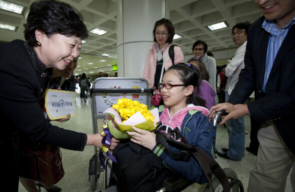  박은경 한국메이크어위시재단 사무총장(왼쪽)이 제주공항에 도착한 혜인이에게 꽃다발을 전하고 있다.