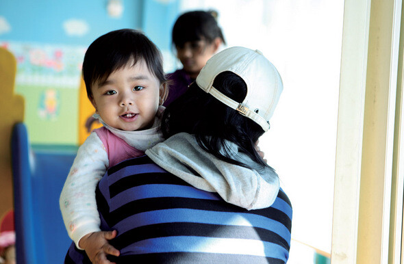 국내에서 태어난 지 1년 된 수헤나가 12월24일 점심시간을 이용해 ‘샬롬의 집’ 보육실을 잠시 찾은 엄마 품에 안겨 해맑은 미소를 짓고 있다.