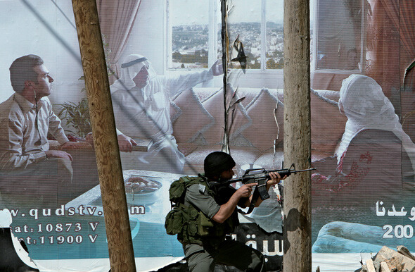 ‘점령의 현실.’ 팔레스타인 땅 요르단강 서안의 헤브론 부근 두라 지역에서 군사작전 중이던 이스라엘 병사가 돌을 던지는 팔레스타인 시위대를 향해 사격 자세를 취하고 있다. 사진 REUTERS/ NAYEF HASHLAMOUN