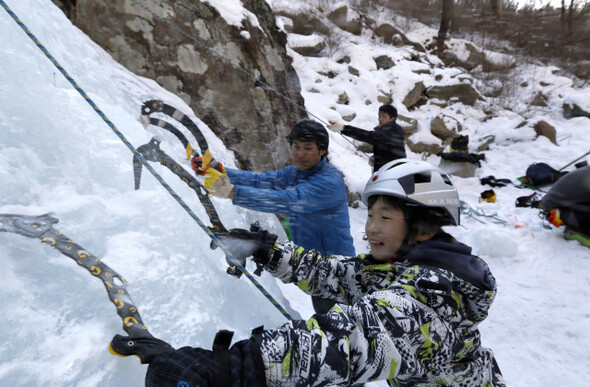 용화산자연휴양림 계곡에서 전문가의 도움으로 빙벽을 오르고 있다.
