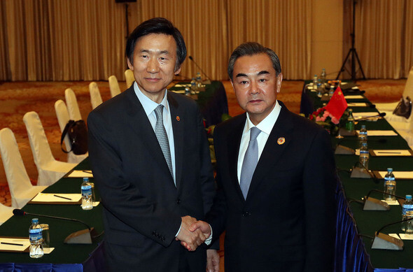 South Korean Foreign Minister Yun Byung-se (left) shakes hands with Chinese Foreign Minister Wang Yi before a bilateral meeting at the Vientiane National Conference in Laos