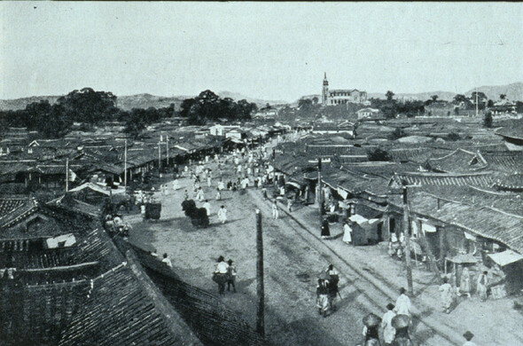 1902년의 서울 남대문로. 멀리 명동성당이 보이고 널찍한 길 한쪽에 전차 궤도가 놓여 있다. 가까이에 있는 길가 집들은 옛 시전 행랑(行廊)의 모습을 간직하고 있지만 현재의 한국은행에 인접한 곳에는 간간이 일본식 지붕도 눈에 띈다. 당시 일본인의 중심 상권은 현재의 신세계백화점에서 롯데백화점에 이르는 거리였다. <꼬레아 꼬레아니>(카를로 로제티 지음)