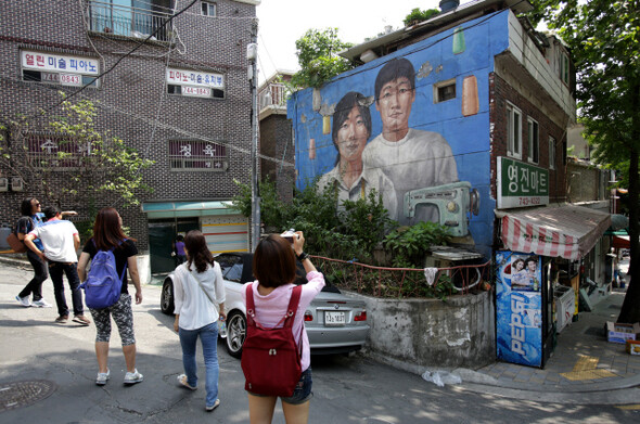 종로구 이화동 벽화마을을 찾은 관광객들이 벽화를 보고 있다. 이곳의 벽화도 벽의 균열로 껍질이 벗겨지고 있다.