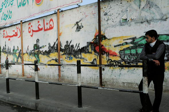 폐허로 변한 가자의 거리에는 이스라엘군의 군사작전 장면이 담긴 벽화가 그려져 있다. 그 곁에서 한 팔레스타인 젊은이가 망연한 표정으로 어딘가를 바라보고 있다.