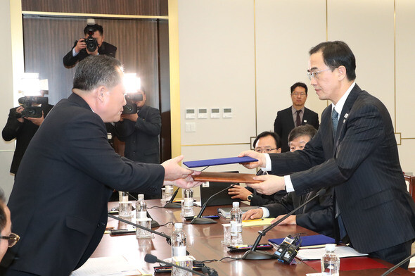 South Korean Minister of Unification Cho Myoung-gyon (left) exchanges joint statements with Ri Son-gwon