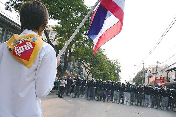 지난 10월7일 한 젊은 PAD 지지자가 타이 국기를 손에 든 채 경찰과 대치하고 있다.