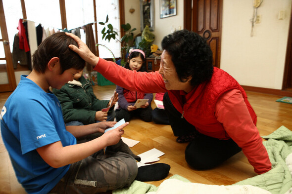 현범이가 자매결연한 이옥자(68) 할머니에게 편지를 읽어주자, 이 할머니가 대견해하며 머리를 쓰다듬어주고 있다.