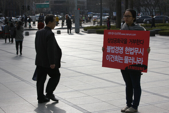 이건희 회장이 복귀한 3월24일 대학생나눔문화 소속 최영지(20·성신여대)씨가 서울 종로 삼성타워 앞 광장에서 이 회장 복귀 반대 손팻말을 들고 1인시위를 하고 있다. <한겨레21> 류우종 기자