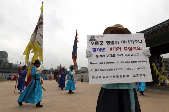 수문장 교대식을 하는 동안 관광객을 통제하려고 관계자가 안내 손팻말을 들고 있다.