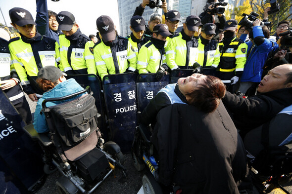 화재로 사망한 뇌성마비 중증장애여성 김주영씨의 노제를 마친 장애인들이 30일 오후 서울 종로구 광화문 도로를 점거하고 24시간 활동보조를 보장하라는 주장하자, 경찰들이 저지를 하고 있다. 김명진 기자 littleprince@hani.co.kr