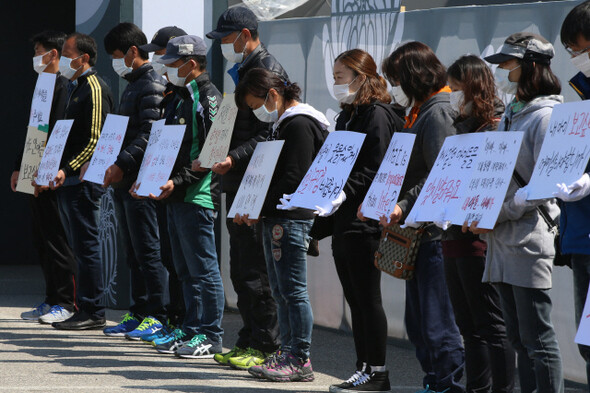  families of missing Danwon High School students wear white masks while holding signs at the memorial altar for victims