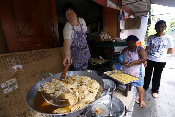 태국의 마을을 여행상품으로 개발하고 있는 사회적기업 로콜어라이크(Local alike) 직원들과 지역 공동체 주민이 27일 태국 방콕 쿠디진 마을에서 마을의 역사와 건물들에 대해 설명을 하고 있다. 오래된 방식으로 빵을 만들고 있는 빠안핀(아판 아줌마 빵집). 방콕/김명진 기자 littleprince@hani.co.kr