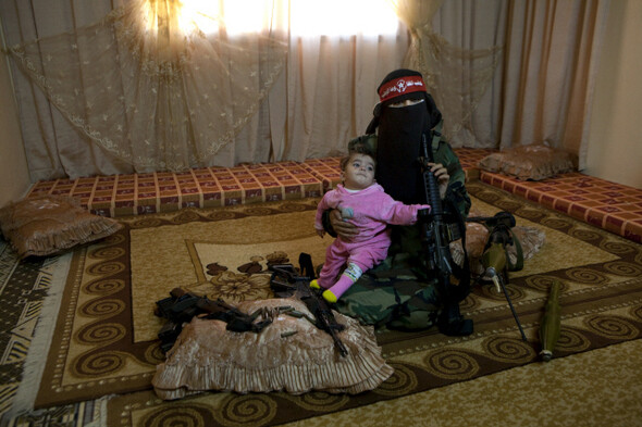 팔레스타인해방민주전선(DFLP)의 23살 여성 부대원이 가자시티에 있는 집에서 자신이 훈련받는 무기들에 둘러싸인 채 9개월 된 여동생을 안고 있다. 2009년 11월. 하이디 러빈