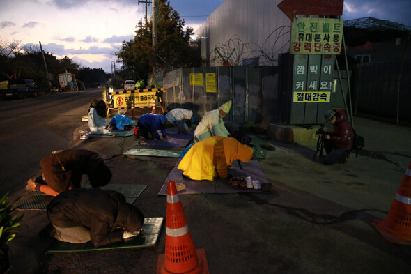 아침 7시 제주 해군기지 공사현장 정문에서 평화활동가와 영화학교 참가자들이 100배를 하는 동안 20대 청년팀이 촬영하고 있다.