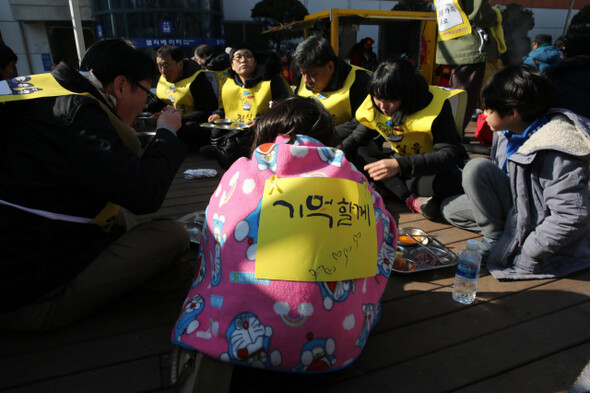경기도 양평에서 가족과 함께 참석한 한 중학생이 담요를 몸에 두른 채 병점역 앞에서 점심 식사를 하고 있다.