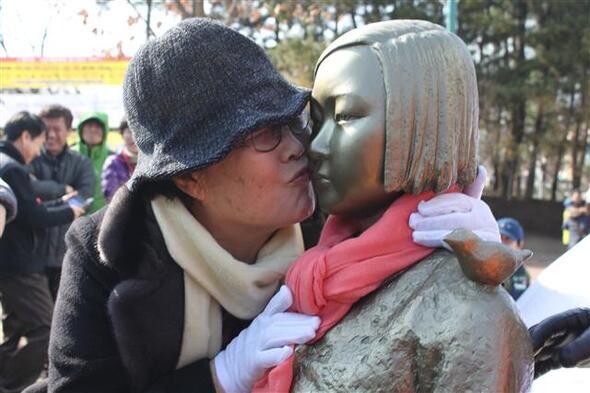 Former comfort woman Lee Yong-soo kisses the newly erected comfort woman statue in Ulsan Grand Park