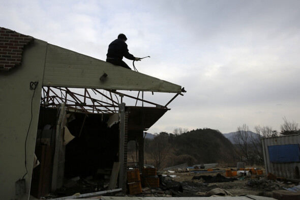 이주민들이 수몰지역에 있는 집 지붕에서 철골 구조물을 분리하고 있다.