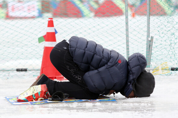 평창 송어축제를 찾은 관광객이 송어잡이를 위해 뚫어놓은 구멍으로 물속 풍경을 하염없이 보고 있다.