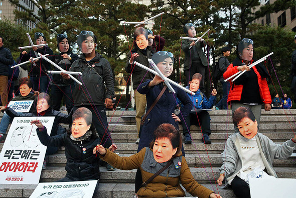 Protesters wear masks while depicting President Park Geun-hye as a puppet of her confidante Choi Sun-sil