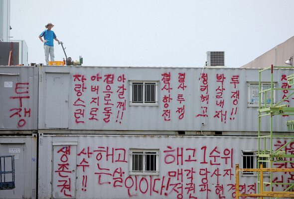 노조가 공장 점거 파업 중인 경기 평택시 칠괴동 쌍용차 공장에서 한 노동자가 ‘정리해고 박살내자’등의 구호가 적힌 컨테이너 위에 올라서 있다. 사진 <한겨레21> 정용일 기자