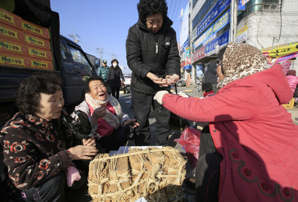 설을 앞두고 차례 용품을 사러 나온 강두리(70·가운데) 할머니가 곶감과 메주를 팔고 있는 아주머니와 밝은 표정으로 이야기꽃을 피우고 있다.