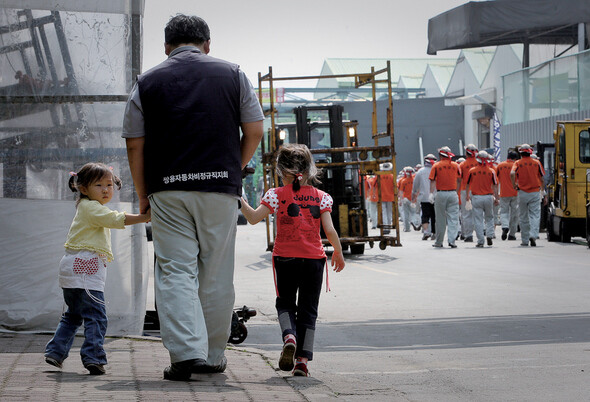 어린 두 딸의 손을 잡고 걸어가는 한 비정규직 노동자의 뒷모습이 무겁다.