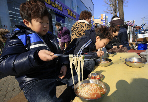 엄마를 따라 장날 구경을 나온 박현빈(8·왼쪽) 어린이가 잔치국수를 먹고 있다.