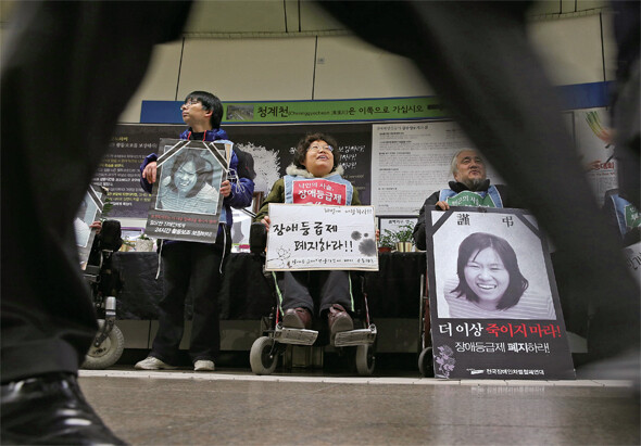 광화문역 지하도에서 숨진 이들의 영정을 들고 관심을 호소하는 장애인들. 이들은 가난한 장애인과 그 가족의 목숨줄을 조이는 부양의무제와 장애등급제의 폐지를 요구하고 있지만, 무심코 지나치는 사람이 많다.한겨레 김정효