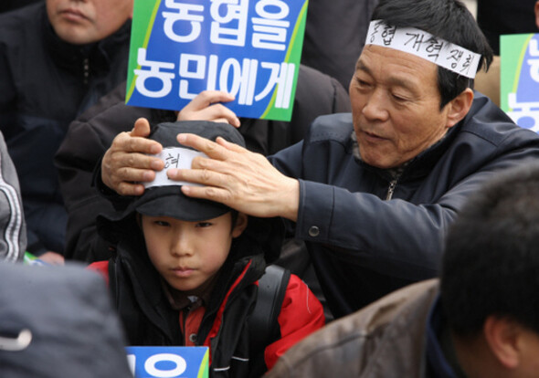 지난 2월25일 오후 서울 여의도 국회 앞에서 전국농민회총연맹이 개최한 농협 개혁 쟁취와 용산 살인 진압 규탄 전국농민대회에 참가한 한 농민이 아이의 머리에 띠를 묶어주고 있다. 류우종 기자