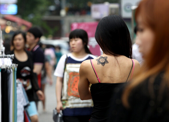어깨에 문신을 한 여성이 거리를 걸어가고 있다.

