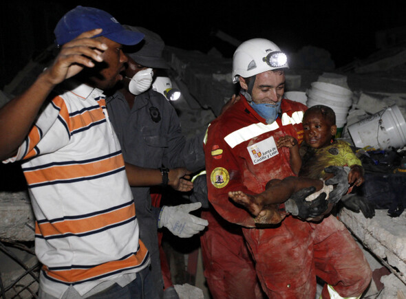 참극 속에서도 기적은 있다. 스페인에서 날아온 구조요원이 1월14일 무너진 건물 더미에서 2살 난 사내아이를 구해내고 있다. 연합/AP