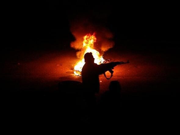 지난 3월17일 시리아의 다마스쿠스 교외에서 한 반군이 불타는 타이어 옆에서 정부군 검문소를 향해 총격을 가하고 있는 모습.