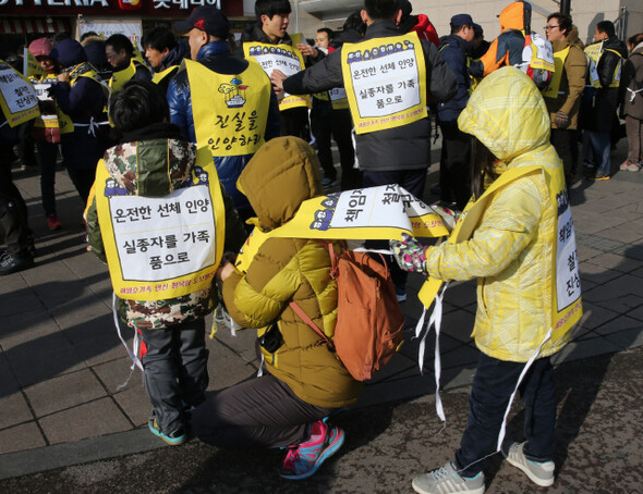 어린 두 아이와 함께 참석한 한 가족이 서로 몸자보를 묶어주고 있다.