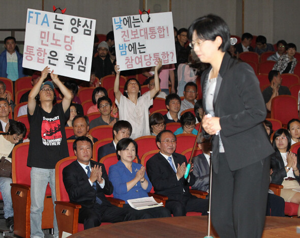 6월26일 서울 송파구민회관에서 열린 진보신당 임시당대회에서 이정희 민주노동당 대표가 축사를 하는 동안 일부 진보신당 당원들이 국민참여당과 합당설에 휘말린 민노당의 행보를 비판하는 피켓시위를 벌이고 있다. 한겨레 박종식