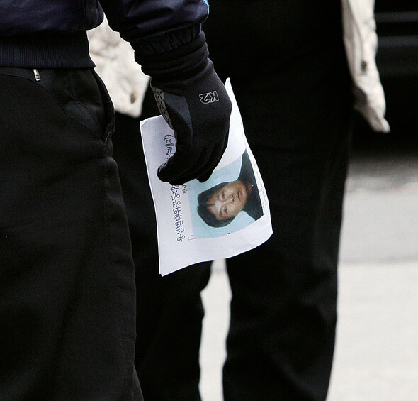 한 경찰이 박래군 위원장의 수배 전단을 들고 서 있다.