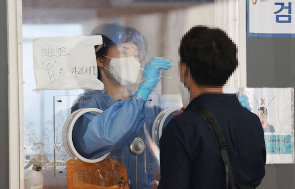A health worker collects a sample to test for COVID-19 at a temporary screening station in Seoul on Thursday. (Yonhap News)