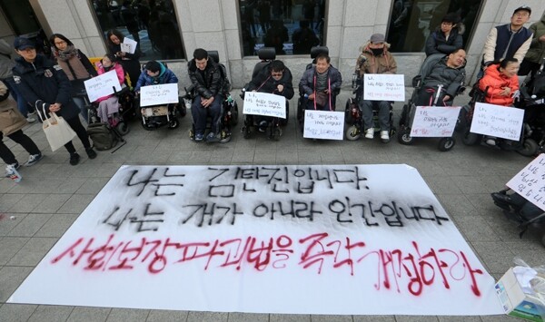 Disabled people in wheelchairs spraypaint their names as a declaration of their humanity