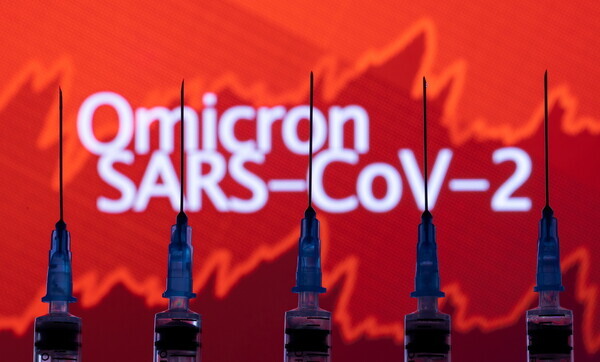 Syringes can be seen in the foreground of graphs of COVID-19 cases and the name of the new variant Omicron. (Reuters/Yonhap News)