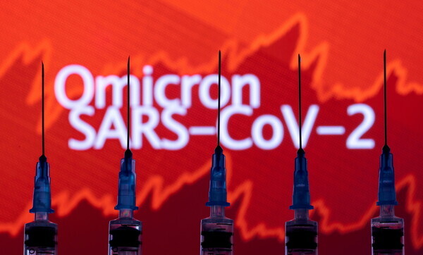 Syringe needles can be seen in front of a screen showing the name of the new COVID-19 variant. (Reuters/Yonhap News)